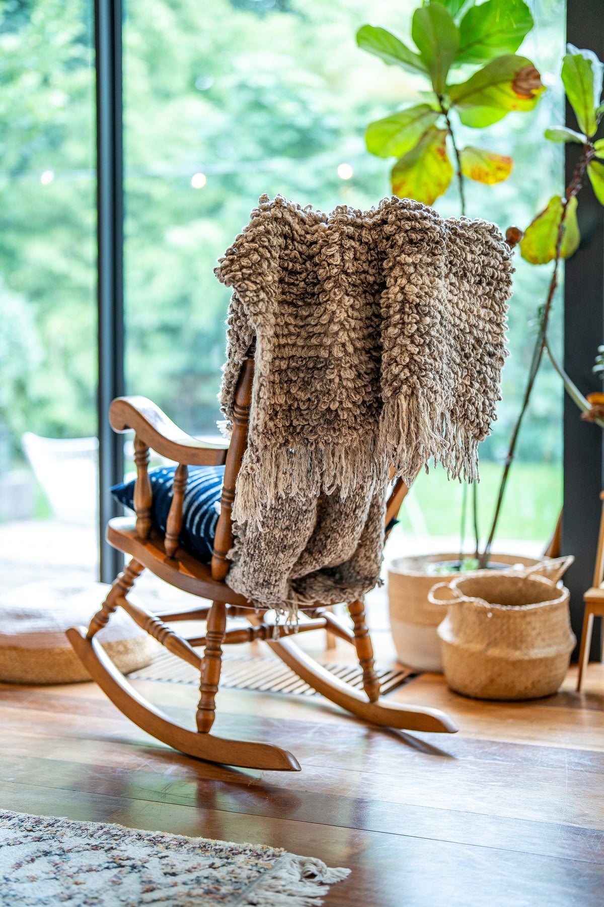 Graumelierte TANGGOOR-Wolldecke mit großen Schlingen über einem Schaukelstuhl am Fenster.