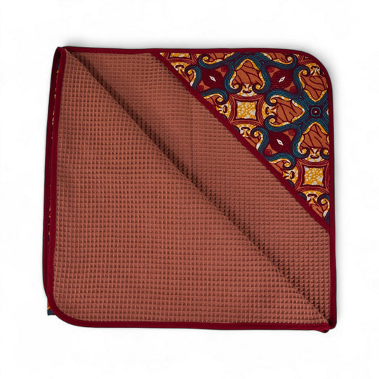 Cape de bain bébé MALAIKA en wax de coton doublé de piqué de coton gaufré nid d'abeille bois de rose. 88 x 88 cm.