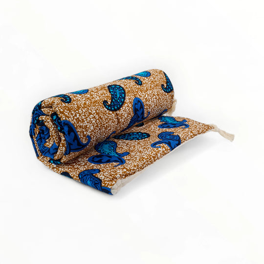 Courtepointe  bi-matière ALA-FARAJA en wax  et double gaze de coton. 
Ses teintes caramel et ses grands motifs cachemire turquoise soulignés de gros pompons écrus insufflent élégance et caractère dans votre chambre ou votre salon. 
Dimensions 110 x 220 cm environ.  
Utilisable en couvre-pied ou en sofa cover, il peut être associé aux housses de coussins du même nom pour un total look.  