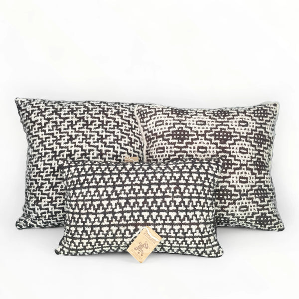 Set de 3 coussins ANASA tricotés artisanalement, en pure laine mérinos. Inserts fournis. Le kit est composé de 2 coussins de 45 x 45 cm et d'un coussin de 30 x 50 cm. Coloris naturels de la laine, écru et chocolat 