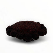 Coussin rond à pompons chocolat BONBONSI en pure laine mérinos, 30 cm de diamètre. Kenana Knitters pour Studio Matonge. Disponible en 2 tailles (30 cm et 50cm de diamètre) et 3 couleurs (blanc écru, beige et marron foncé). Insert fourni