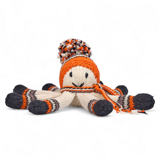 Doudou pieuvre NAIA en laine tricotée main, bonnet à pompon multicolore et tentacules rayées mandarine, noir et brun, vue de face.