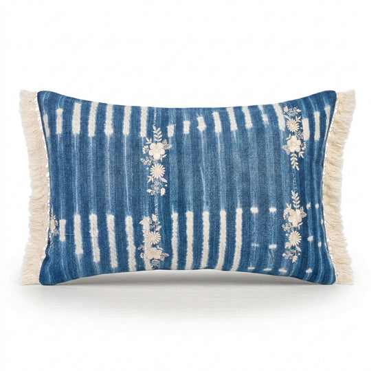 Housse de coussin à franges ZABUNI-ZARI, en indigo vintage upcyclé, rehaussé de broderies fleuries blanc ivoire. 
Pièces uniques : l'emplacement et la quantité de broderies, ainsi que l'emplacement des motifs dans la trame diffère sur chaque pièce.