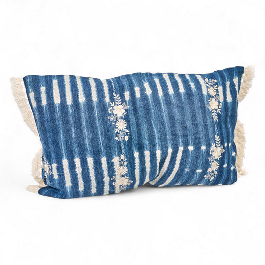 Housse de coussin à franges ZABUNI-ZARI, en indigo vintage upcyclé, rehaussé de broderies fleuries blanc ivoire. 
Pièces uniques : l'emplacement et la quantité de broderies ainsi que l'emplacement des motifs dans la trame diffère sur chaque pièce.