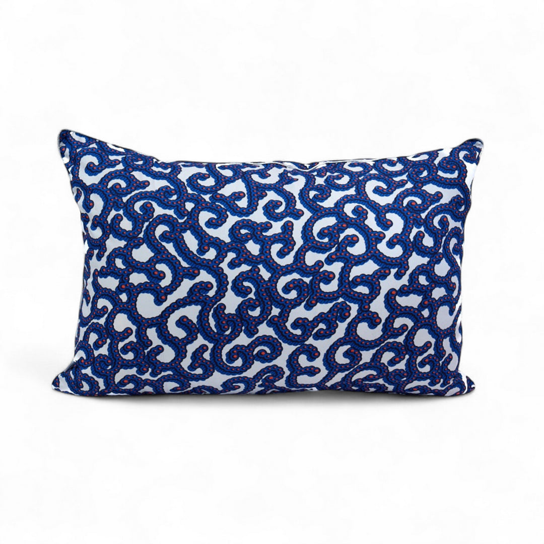 OSUN-KOORAAL, housse de coussin ethnique 
wax blanc, bleu, corail réhaussé d'un passepoil argenté  40 x 60 cm Studio Matongé