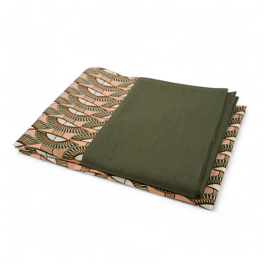 Nappe GIDA_SENI pliée sur fond blanc. Bord en lin kaki et centre en wax kaki,, rose et blanc.
parfaite avec une vaisselle vintage pour une table originale et personnelle. 
Ici carrée : 130 x 130 cm. Existe aussi en format rectangulaire 158 x 250 cm .
A assortir avec nos serviettes AYO ou SAVUTI.
