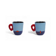 Tasse MARABA en céramique bleu clair et bleu nuit, anse rouge, deux angles révélant la touche orange peinte.