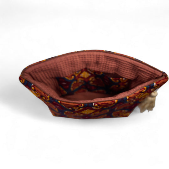 Trousse de toilette MALAIKA en wax de coton multicolore, doublé de piqué de coton gaufré nid d'abeille bois de rose. La trousse MALAIKA de Studio Matongé est agrémentée d'un joli pompon de coton. Dimensions : 38 x 29 cm