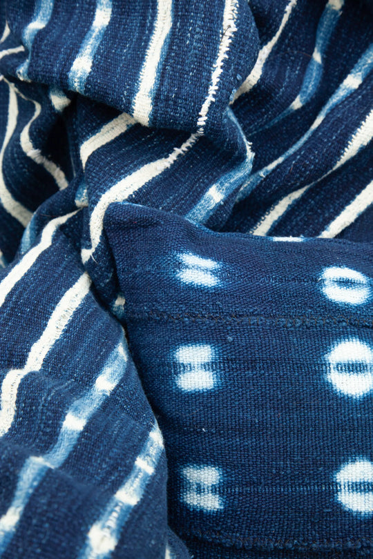 Housse de coussin ethnique en bogolan indigo BAHARINI. Entièrement réalisée à la main. Housse de coussin zippée rectangle 30 x 50 cm. 100% coton bio. Tissage et teinture artisanaux réalisés au Mali. Confection réalisée en Belgique. Plaid vintage doublé FARABALE.