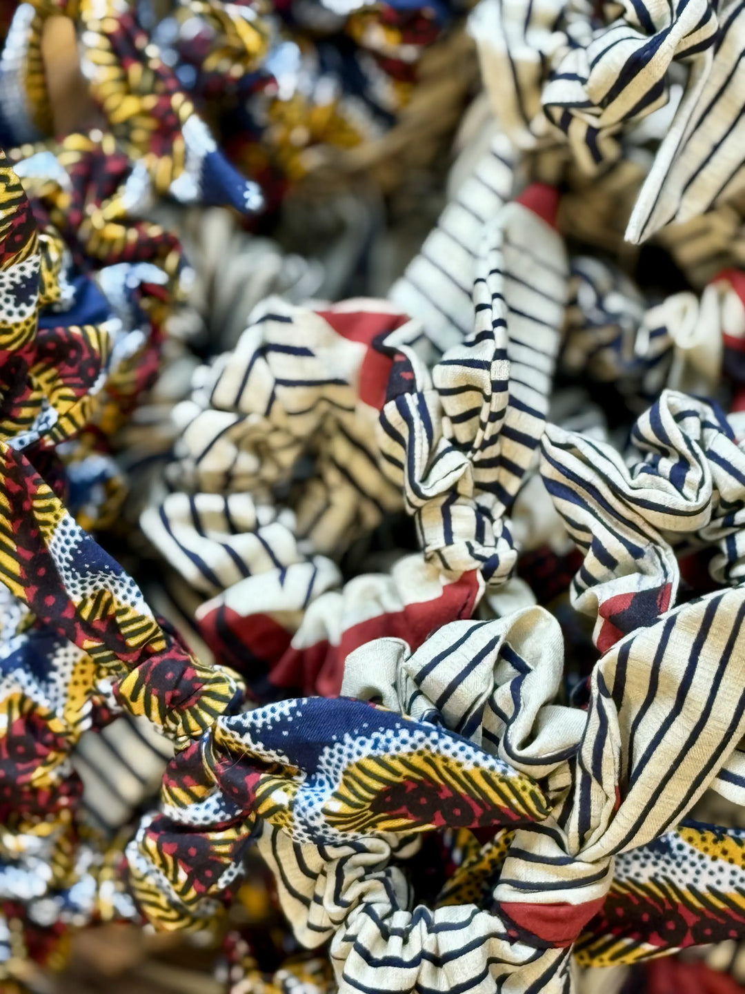 Chouchous MOYO en wax faits main en Belgique – nœud amovible et tissu upcyclé, chaque pièce unique, présentation de modèles variés aux motifs colorés.