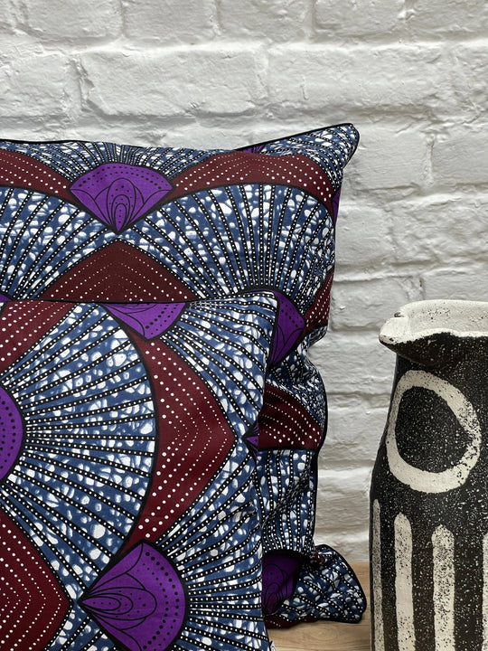 Housse de coussin ethnique OSUN-SANAA en wax multicolore aux dominantes bleues, bordeaux et violet par Studio Matongé. 100% coton - Disponible en différents formats et dimensions. 