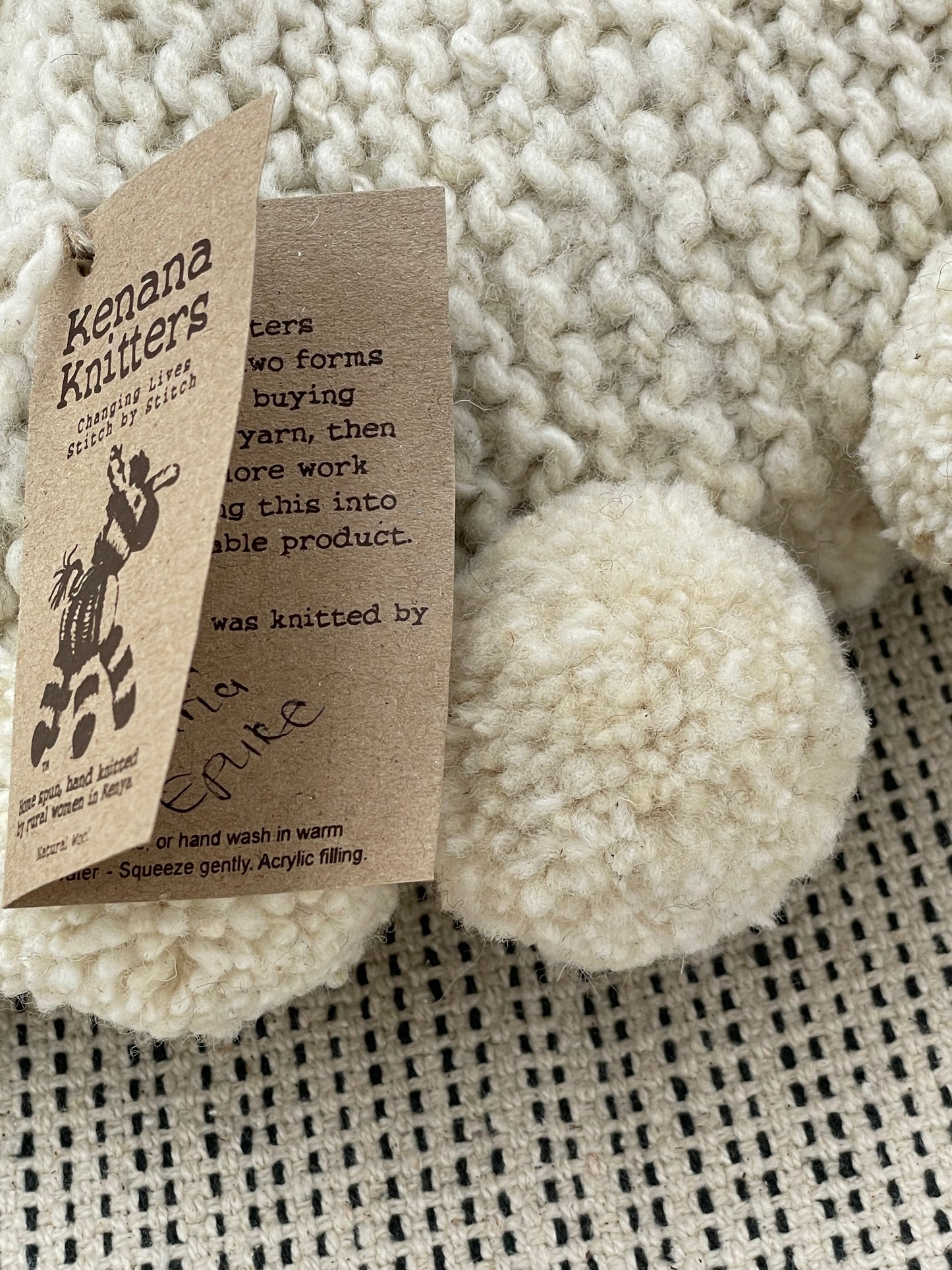 Chaque coussin rond à pompons BONBONSI en pure laine mérinos est tricoté main par les femmes de la coopérative Kenana Knitters. Unique, chaque pièce porte fièrement la signature de l'artisane qui l'a réalisée.