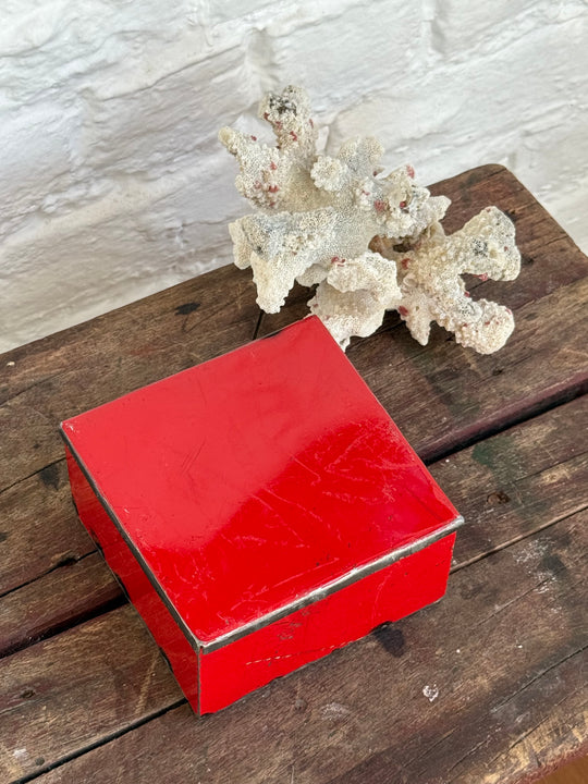 Boîte RANGI rouge fermée, vue de trois quarts avec u corail décoratif blanc en arrière plan