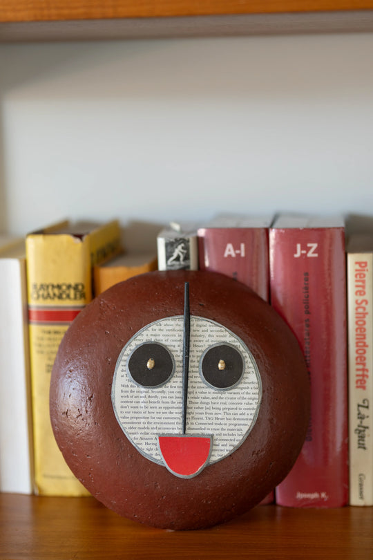 Masque africain stylisé design réalisé en papier mâché recyclé - TUTU - Quazidesign - Studio Matongé 
posé devant des livres