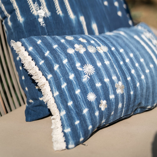 Housse de coussin à franges ZABUNI-ZARI, en indigo vintage upcyclé, rehaussé de broderies fleuries blanc ivoire. 30 x 50 cm. 
Ici en mix and match avec une housse de coussin en indigo vintage BUUM-ZARI, également upcyclée et brodée. 
Pièces uniques : l'emplacement et la quantité de broderies ainsi que l'emplacement des motifs dans la trame diffère sur chaque pièce. 