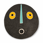 Masque mural rond noir en papier mâché peint jaune et bleu, décoration murale artisanale graphique sur fond blanc. Modèle ZUMA - diamètre 35 cm.