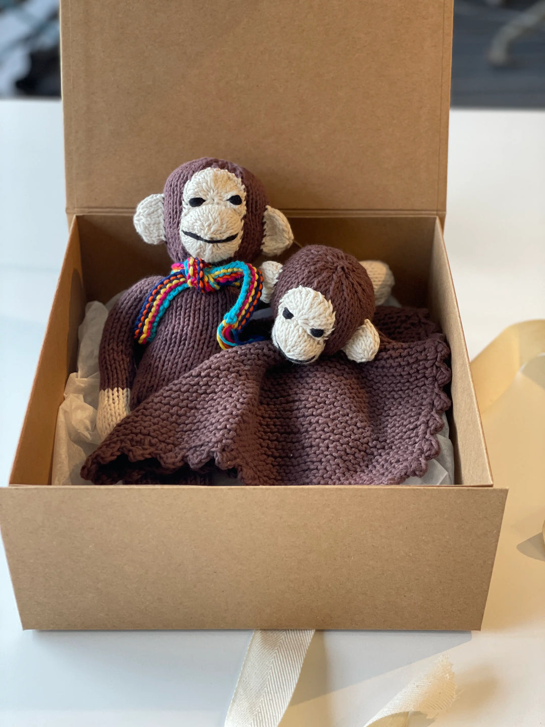 Box cadeau de naissance singes pour nouveau-né. Notre box contient un doudou plat et un doudou longues pattes coordonnés, proposés dans une élégante boite en kraft à fermeture aimantée réutilisable. 