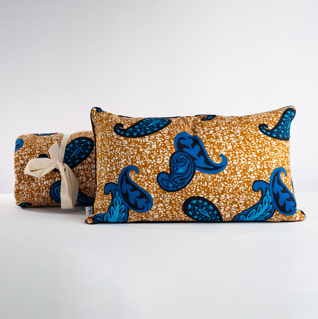 La housse de coussin et courtepointe FARAJA en wax  de coton caramel aux motifs cashmere bleu  : un mariage de couleurs éclatant qui allie chaleur et modernité.
En combinaison sur un lit ou un canapé la courtepointe et la housse de coussin FARAJA se combinent à merveille avec notre plaid TANGOOR et un coussin uni MSINGI ou BONBONSI.