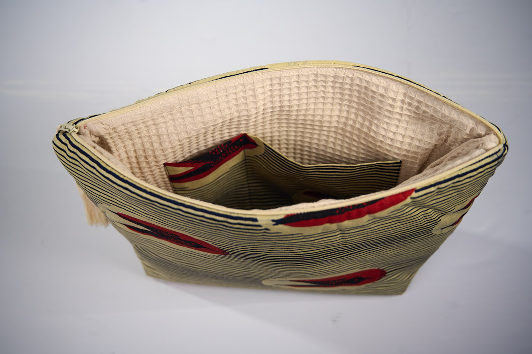 Trousse de toilette MTOTO en wax de coton hirondelle doublé de piqué de coton gaufré nid d'abeille écru, agrémentée d'un joli pompon de coton. Dimensions : 38 x 29 cm