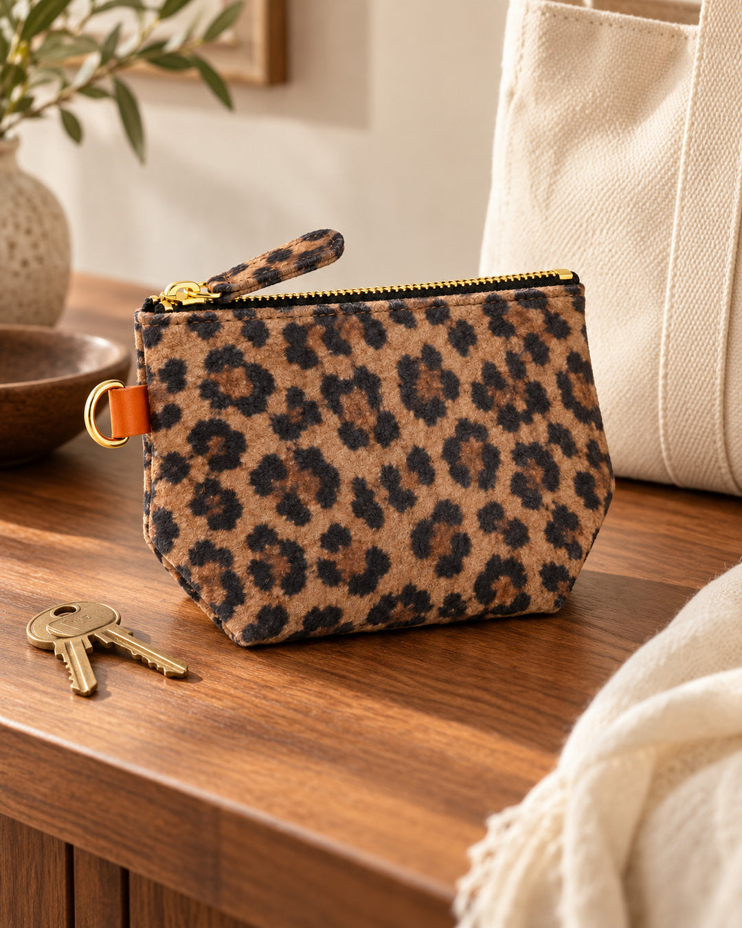 CHOU portemonnee van Isabelle Varin van leer met luipaardprint, op een houten sidetable naast sleutels.