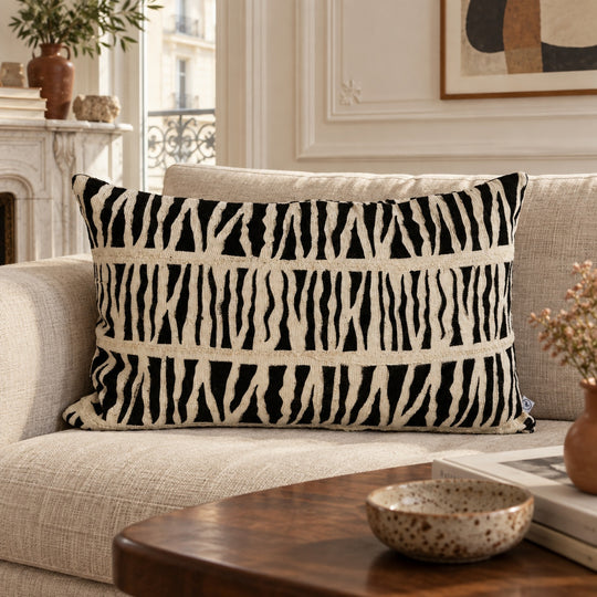 Coussin IDUBE 45 × 70 cm en bogolan zébré noir et écru sur un canapé en lin dans un salon lumineux.