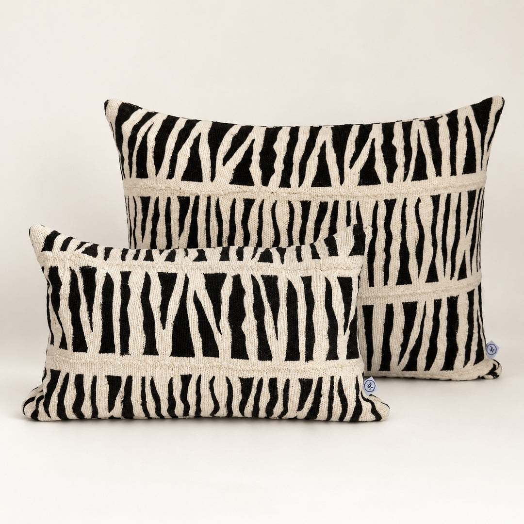 Coussins IDUBE en bogolan zébré noir et écru, formats 30 × 50 et 45 × 70 cm, réunis sur fond clair.