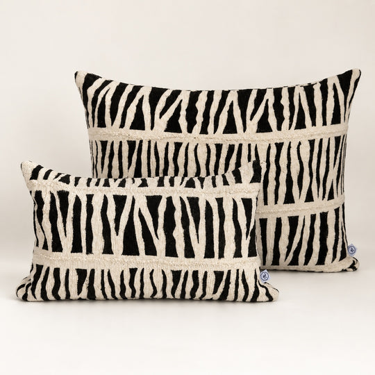 Coussins IDUBE en bogolan zébré noir et écru, formats 30 × 50 et 45 × 70 cm, réunis sur fond clair.