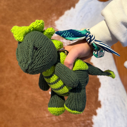 ELIOT, le doudou dragon de Studio Matongé en coton bio certifié GOTS, avec le chouchou MOYO-MTOTO vert.   