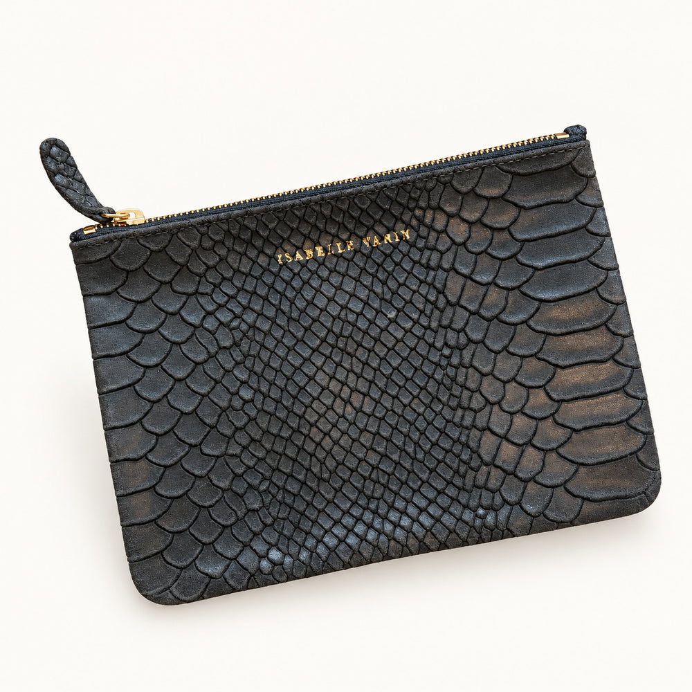 MONOÏ-Etui von Isabelle Varin aus schokoladenbraunem Nubukleder mit Kroko-Prägung, vor hellem Hintergrund.