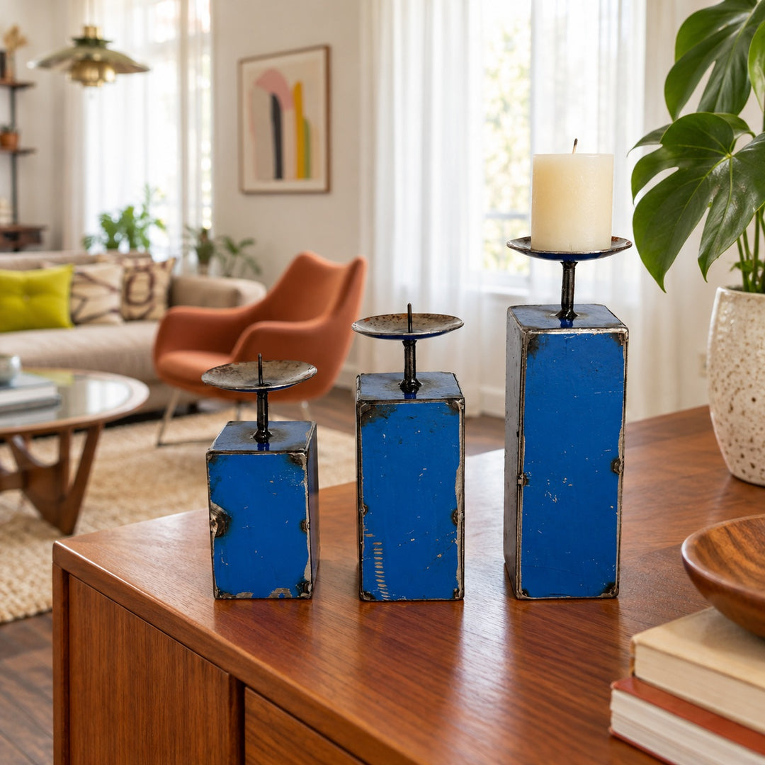 Trois bougeoirs NURU en métal recyclé bleu sur un buffet en bois dans un salon vintage lumineux.