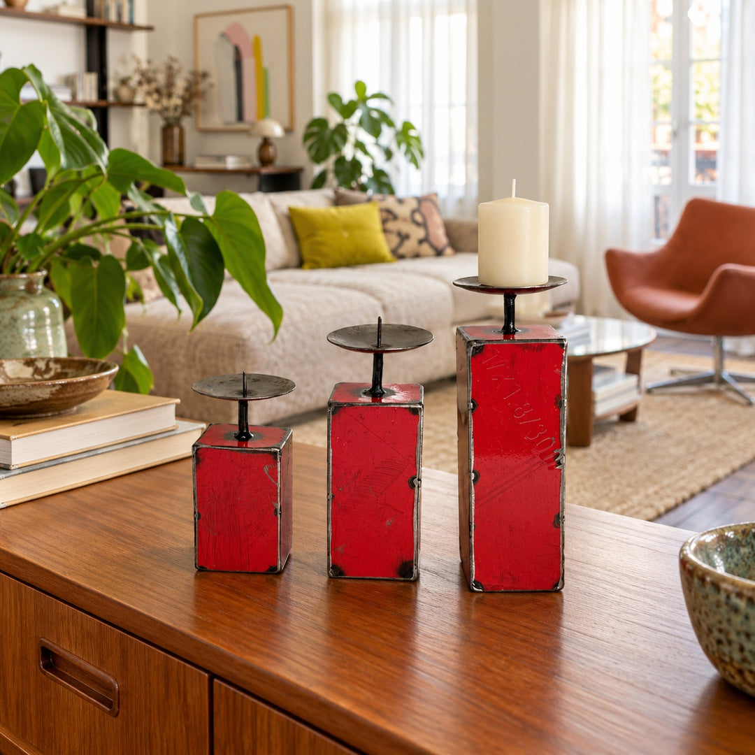 Trois bougeoirs NURU en métal recyclé rouge sur un buffet en bois dans un salon vintage lumineux.