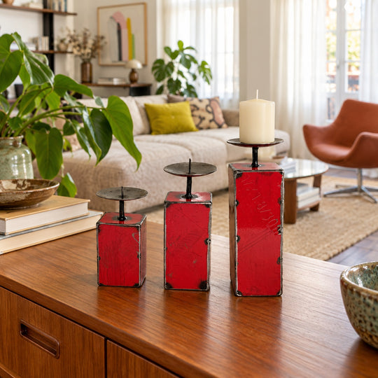 Trois bougeoirs NURU en métal recyclé rouge sur un buffet en bois dans un salon vintage lumineux.