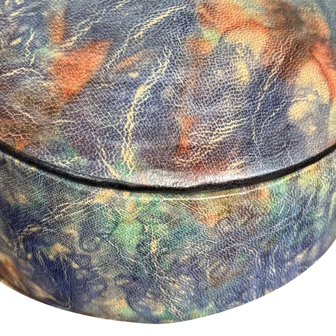 Gros plan sur le grain du cuir marbré bleu, turquoise et orange et la jonction du couvercle de la boîte.