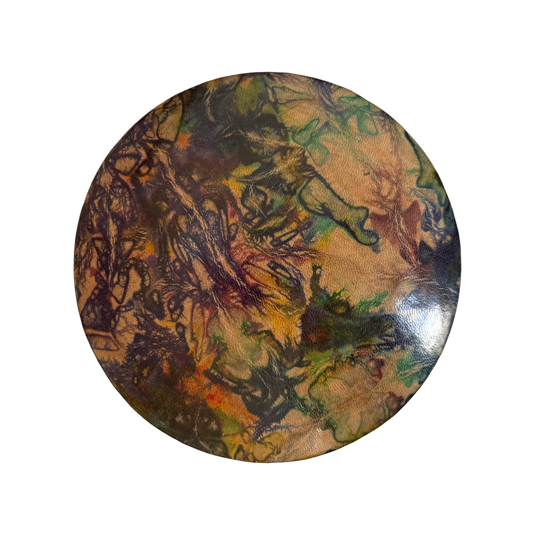 Couvercle rond en cuir marbré violet, vert et ocre, vu du dessus sur fond blanc.
