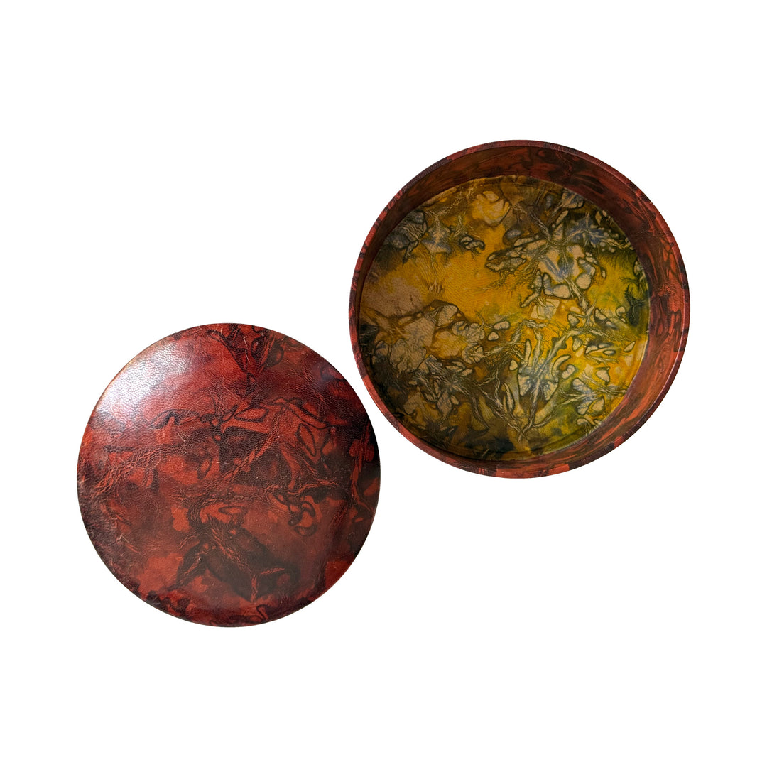 Boîte ronde en cuir rouge rouille et brun, ouverte sur un intérieur marbré jaune, avec son couvercle à côté.