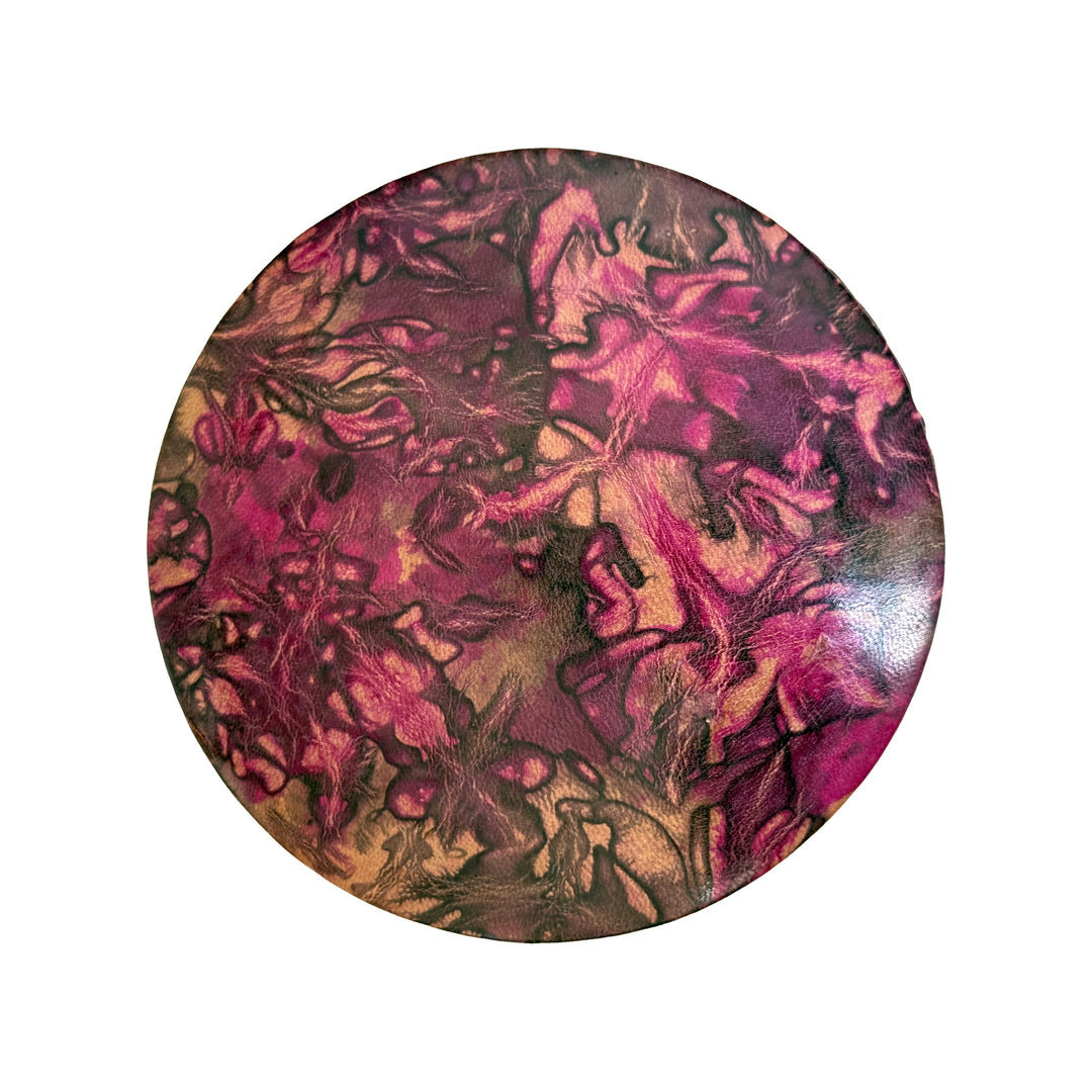 Couvercle rond en cuir marbré rose fuchsia, prune et beige, vu du dessus sur fond blanc.