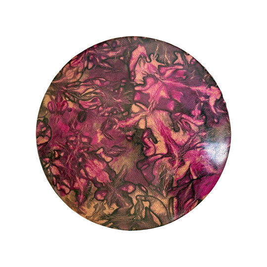 Couvercle rond en cuir marbré rose fuchsia, prune et beige, vu du dessus sur fond blanc.