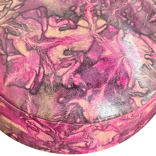 Gros plan sur le grain du cuir marbré rose fuchsia, prune et beige et la jonction du couvercle de la boîte.