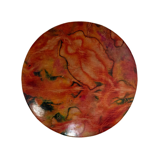 Couvercle rond en cuir marbré corail, orange et vert, vu du dessus sur fond blanc.