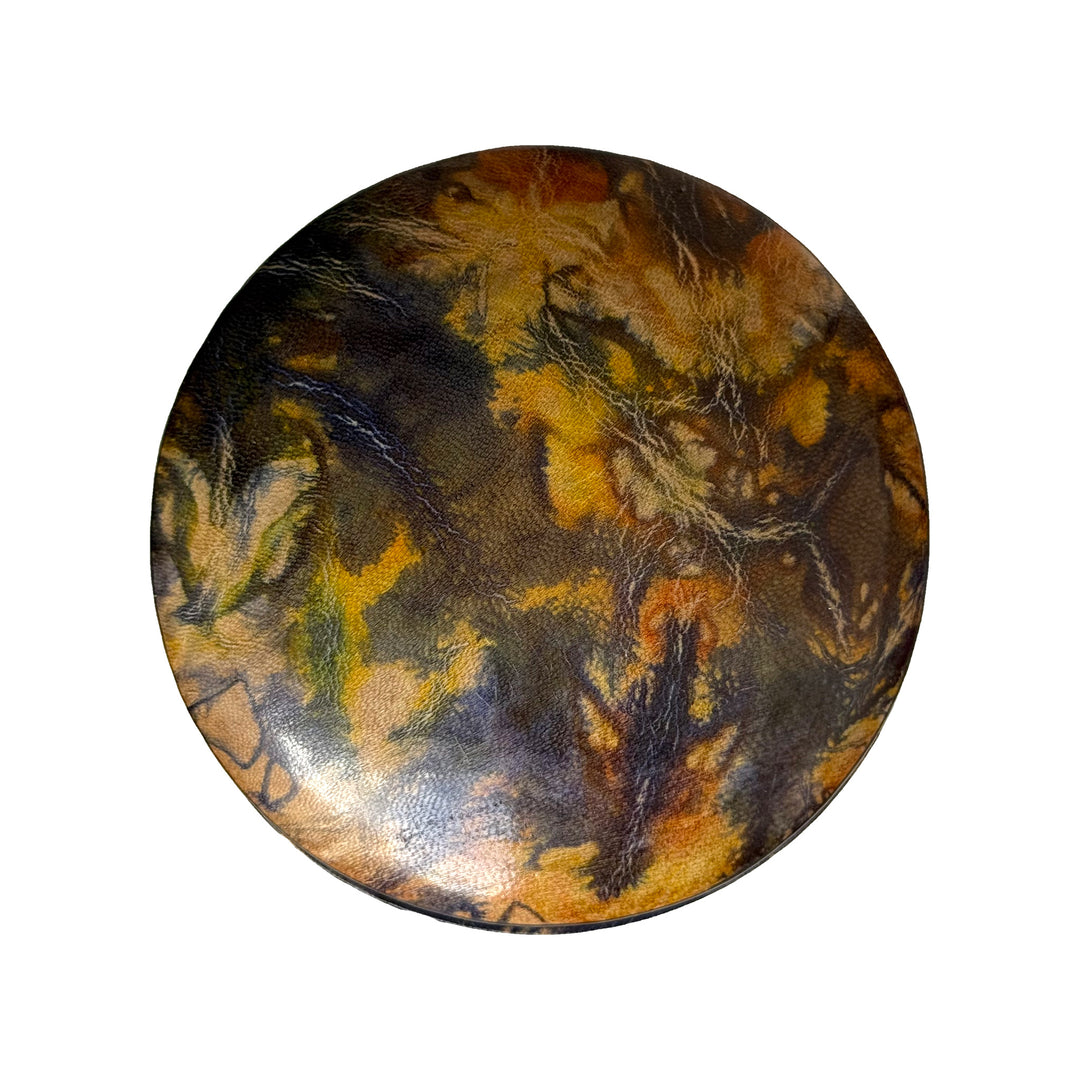 Couvercle rond en cuir marbré violet et jaune ocre, vu du dessus sur fond blanc.