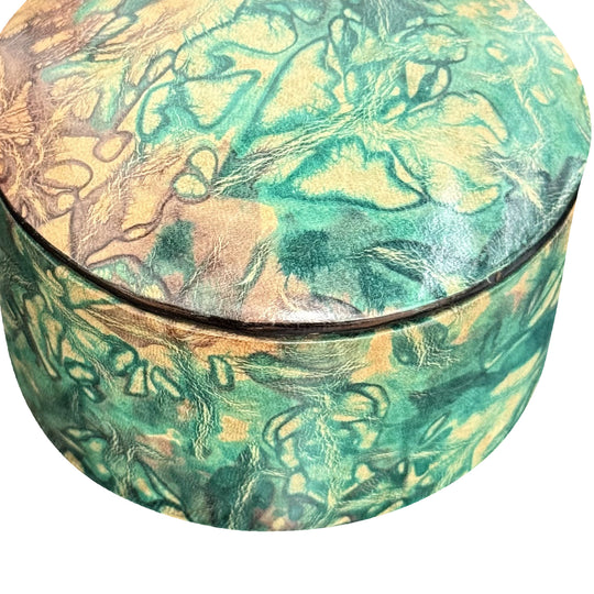 Gros plan sur le grain du cuir marbré vert turquoise et beige et la jonction du couvercle de la boîte.