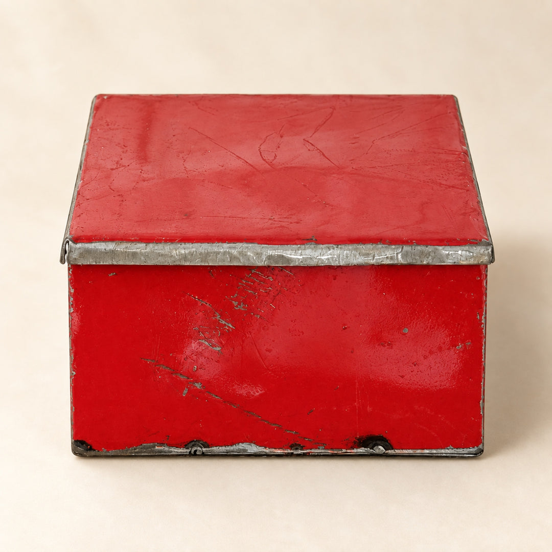 Boîte RANGI rouge fermée sur fond clair, en métal recyclé avec une peinture patinée et des bords en métal brut.