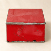 Boîte RANGI rouge fermée sur fond clair, en métal recyclé avec une peinture patinée et des bords en métal brut.
