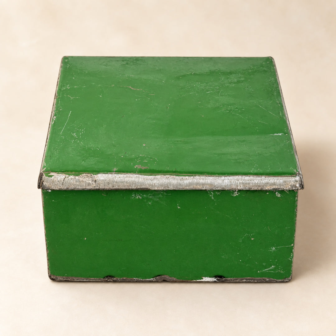 Boîte RANGI verte fermée sur fond clair, en métal recyclé avec une peinture patinée et une bordure de couvercle en métal brut.